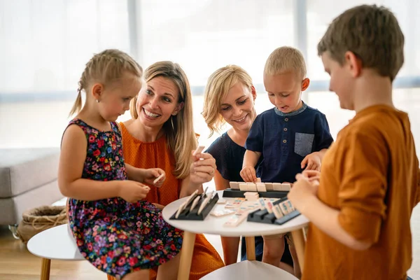 子供と一緒にボードゲームをプレイテーブルの若い女性 保育園 子供時代のコンセプト — ストック写真
