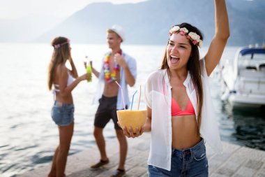 Bir grup arkadaş sahilde eğleniyor ve kokteyl içiyor.