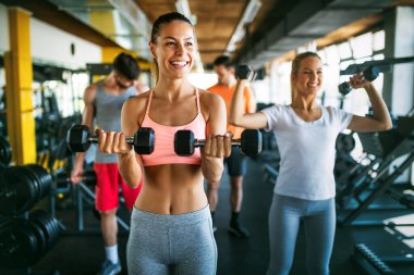 Sağlıklı kalmak için spor salonunda egzersiz yapan sağlıklı bir grup genç. Spor, dostum, egzersiz konsepti