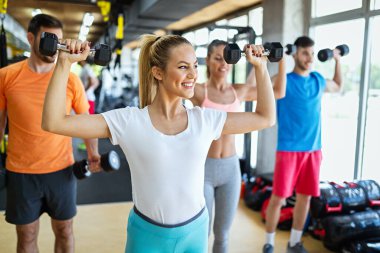 Sağlıklı kalmak için spor salonunda egzersiz yapan sağlıklı bir grup genç. Spor, dostum, egzersiz konsepti