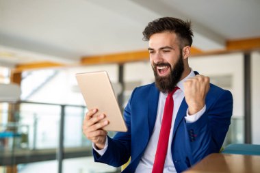 Ofiste tableti üzerinde çalışan yakışıklı bir iş adamı.