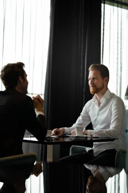 İki iş adamı kahve dükkanında Brerak projesini tartışıyor.