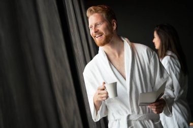 Bornozlu bir erkek çay ve kahve içerken dinleniyor.