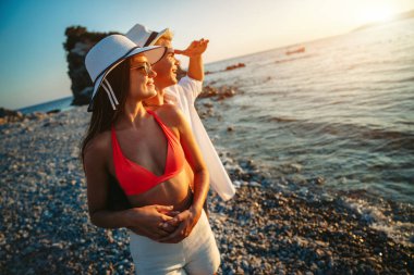 Kumsalda aşık çekici genç bir çift, yaz tatilinin tadını çıkarıyor, seyahat ediyor.