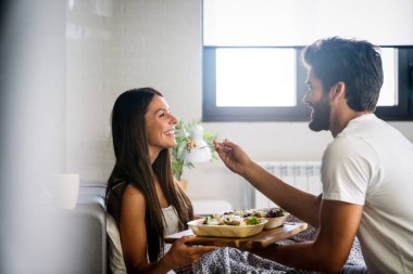 Yatakta rahat ve mutlu bir kadına kahvaltı tepsisi uzatıyorum. Çift aşk konsepti.