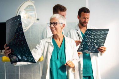 Bir grup doktor tomografiye bakıyor, teşhis koymak için hastanede MRI taraması yapıyorlar.