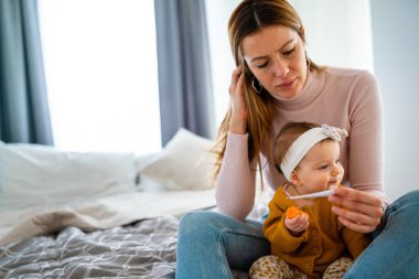 Anne hasta çocuğunun ateşini ölçüyor. Yüksek ateşi olan hasta bir çocuk ve annesi termometreyi tutuyor.
