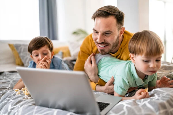 Evde dizüstü bilgisayara bakıp eğlenen sevimli bir aile.