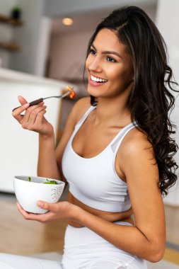 Güzel, uyumlu, mutlu kadın spor yaptıktan sonra sağlıklı salata yiyor.