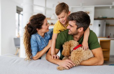 Mutlu genç aile eğleniyor, evde köpeklerle oynuyorlar.