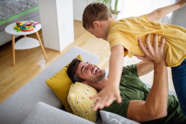 Mutlu aile kavramı. Yakışıklı baba evde oğluyla oynuyor..