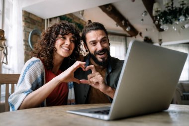 Genç mutlu çift evde online aile görüntülü görüşme yapıyor.