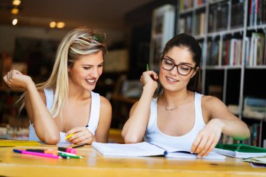 Mutlu üniversite öğrencileri üniversitede kitaplarla okuyorlar.