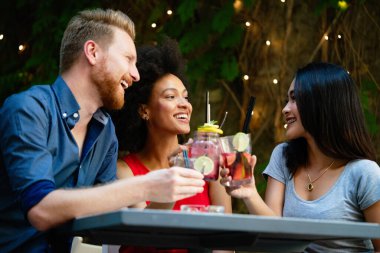 Genç mutlu arkadaşlar birlikte harika vakit geçiriyorlar. Bir grup insan konuşuyor ve gülümsüyor..