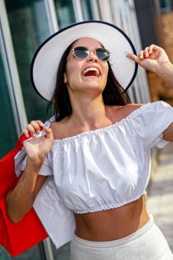 Çantası olan mutlu genç bir kadın alışveriş ve seyahatin tadını çıkarıyor. Tüketim, alışveriş, yaşam tarzı konsepti