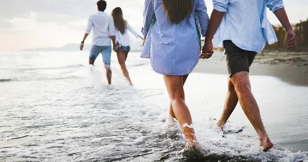 Bir grup arkadaş gün batımında sahilde yürüyor ve eğleniyorlar.