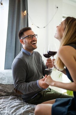 Mutlu güzel çift evde sarılıp kırmızı şarap içiyor.
