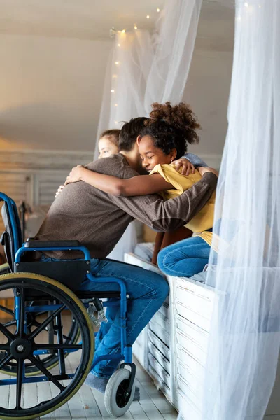 幸せは家族の概念を愛する 家で子供と抱き合う車椅子の障害者の笑顔の父 — ストック写真