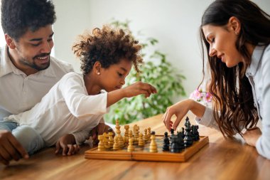 Ebeveynler ve çocuklar evde birlikte vakit geçirirken satranç oynuyorlar. Aile sevgisi kavramı