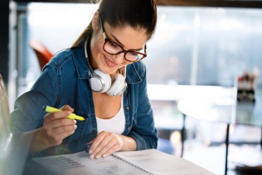 Güzel kız öğrenci ödevini yapıyor, çalışıyor, sınava hazırlanıyor. Üniversite, eğitim, halk konsepti