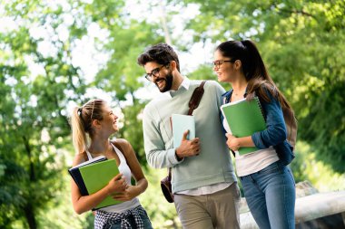 Mutlu üniversite öğrencileri üniversitede kitaplarla okuyorlar.