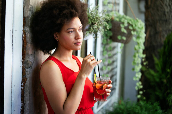 Fashion portrait of sexy pretty african woman with drink outdoor