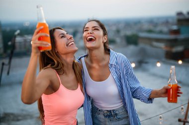 Bir grup arkadaş çatıdaki bir partide eğleniyor ve kokteyl içiyorlar..