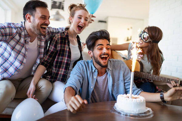 Group of happy friends celebrating birthday together at home