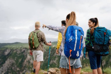 Bir grup mutlu arkadaş, sırt çantalı insanlar birlikte yürüyüş yapıyor.