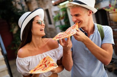 Bir grup mutlu turist yaz tatilinde eğleniyor, pizza yiyor.