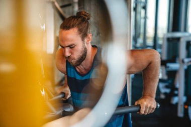 Spor salonunda makine üzerinde egzersiz yapan yakışıklı bir adam.