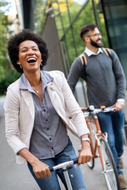 Şehirde elektrikli scooter ve bisiklet kullanan mutlu bir çift. Sıfır emisyonlu yeşil eko enerji kavramı