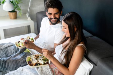 İyi sabahlar. Yatakta sağlıklı bir kahvaltı. Genç ve güzel bir çift birlikte vakit geçiriyorlar.