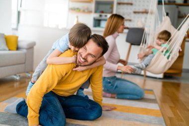 Evde oynayan ve sarılan çocuklu mutlu bir aile. Mutluluk, insanlar, ebeveynlik, çocukluk kavramı.