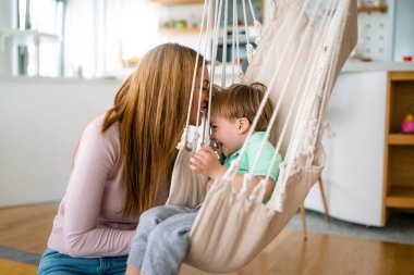 Neşeli çocuk eğleniyor, annesiyle birlikte evde oyun oynuyor. Tek ebeveynlik, mutluluk, çocukluk kavramı.