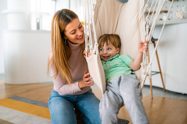 Joyful toddler boy having fun, playing with his mother together at home. Single parenting, happiness, childhood concept.