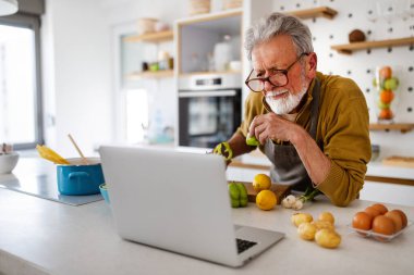 Mutfakta yemek pişiren olgun, mutlu bir adam. Emeklilik, hobi insanlar konsepti