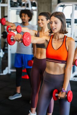 Spor salonunda sağlıklı kalmak için egzersiz yapan bir grup fit insan.