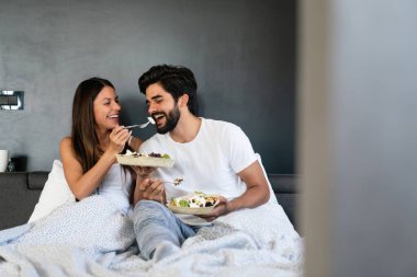 Yatakta sağlıklı bir kahvaltı. Genç ve güzel bir çift yatakta kahvaltı yapıyor..
