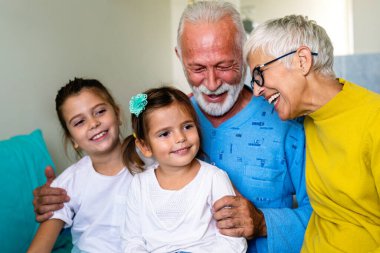 Mutlu büyükanne ve büyükbabalar evde torunlarıyla eğleniyor.
