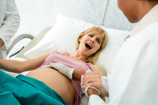 Woman giving birth in hospital with medical doctor team. Healthcare child birth people concept