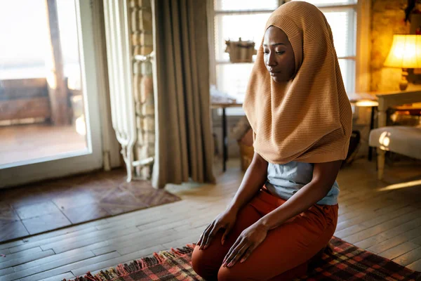 Young muslim black woman praying at home. People religion concept