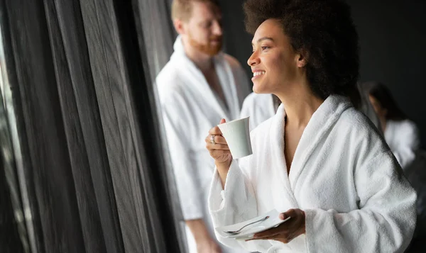 美しい女性リラックスで高級ホテルのスパを身に着けていますバスローブ窓を見てコーヒーを飲む — ストック写真