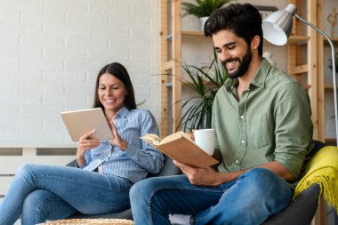 Evde güzel vakit geçiriyorum. Güzel, genç bir çift birbirlerine bağlanıyorlar ve kitap, tablet okurken gülümsüyorlar..