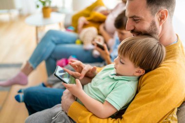 Mutlu baba ve oğul evde cep telefonuyla oyun oynuyor. Teknoloji bağımlılığı aile sorunu kavramı