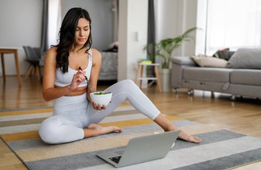 Güzel, uyumlu, mutlu kadın spor yaptıktan sonra sağlıklı salata yiyor.