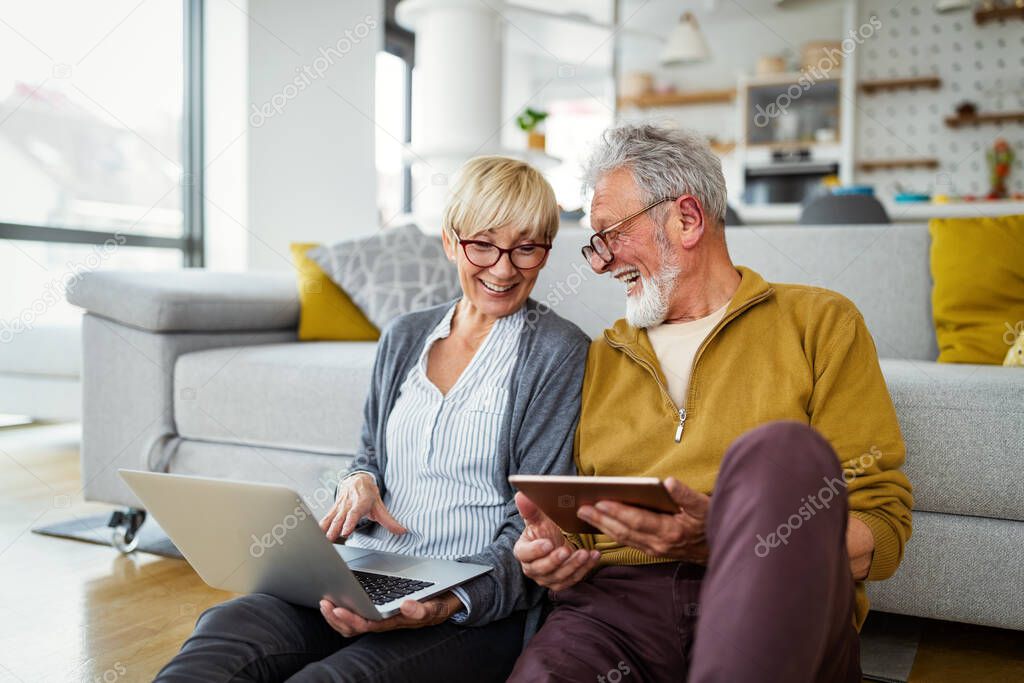 Senior couple websurfing on internet with laptop at home. Technology people concept