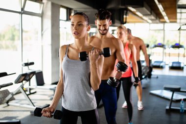 Spor salonunda egzersiz yapan bir grup mutlu zinde genç insan. Spor helatı yaşam tarzı konsepti