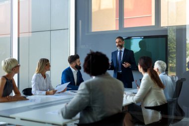 Çeşitli iş adamları toplantıda birlikte çalışıyor. Mali belgeleri inceliyorlar.