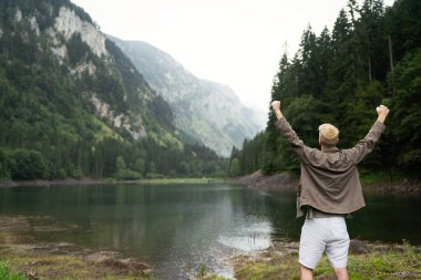 Aktif genç yürüyüşçü, manzaranın tadını çıkarıyor, dağ manzarasına bakıyor.